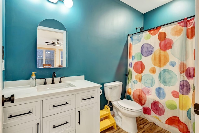 bathroom featuring toilet, vanity, curtained shower, ceiling fan, and hardwood / wood-style floors