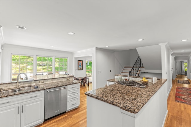 kitchen with white cabinetry, dishwasher, sink, and dark stone countertops