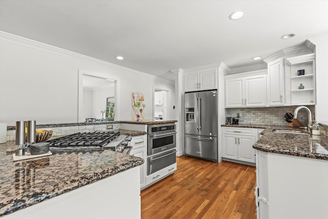 kitchen featuring stainless steel appliances, white cabinetry, sink, and dark stone counters