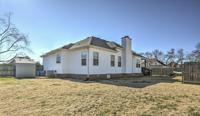 rear view of property with central AC, a lawn, and a storage unit