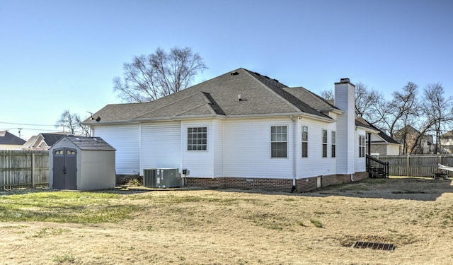 back of property with a yard, central AC unit, and a shed