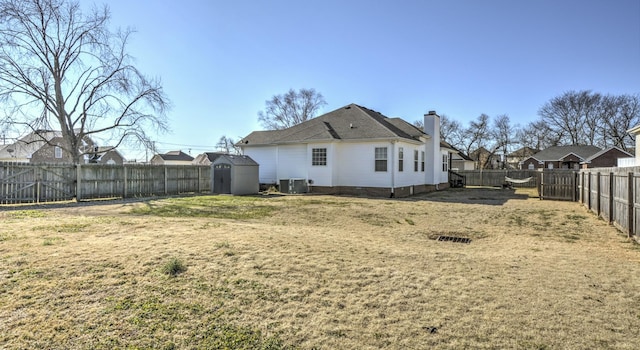 back of property featuring a lawn, central AC unit, and a shed