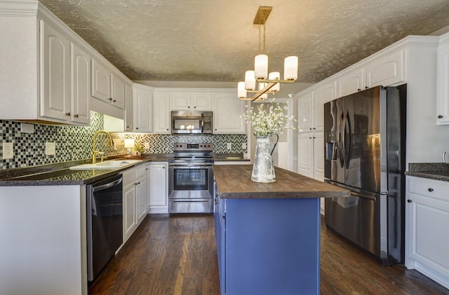 kitchen with pendant lighting, sink, appliances with stainless steel finishes, white cabinets, and a kitchen island