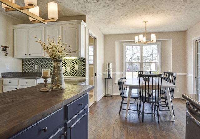 dining space featuring a notable chandelier, dark wood-type flooring, and a textured ceiling