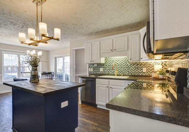 kitchen with sink, white cabinetry, decorative light fixtures, appliances with stainless steel finishes, and a kitchen island