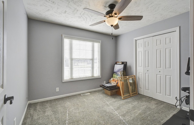 sitting room with ceiling fan, carpet, and a textured ceiling