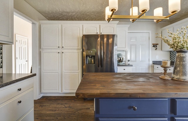 kitchen featuring butcher block countertops, stainless steel fridge, and white cabinets