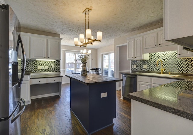 kitchen with sink, a center island, pendant lighting, stainless steel appliances, and white cabinets