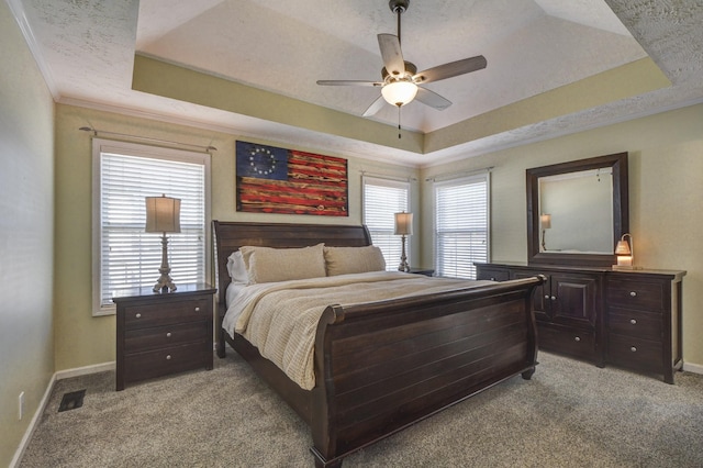 carpeted bedroom with ceiling fan, ornamental molding, a tray ceiling, and a textured ceiling