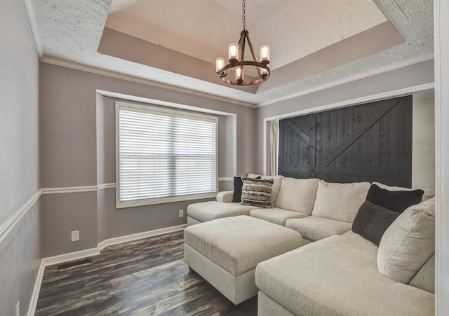 living room featuring crown molding, dark hardwood / wood-style floors, a chandelier, and a tray ceiling