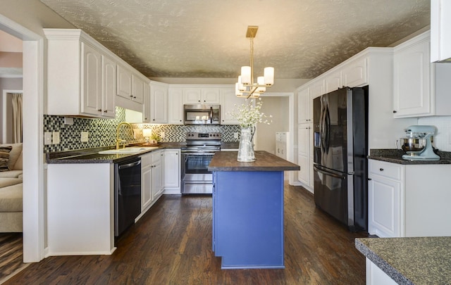 kitchen with sink, hanging light fixtures, appliances with stainless steel finishes, a kitchen island, and white cabinets