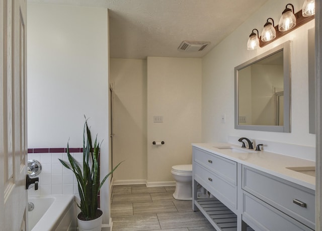 full bathroom featuring independent shower and bath, vanity, a textured ceiling, and toilet