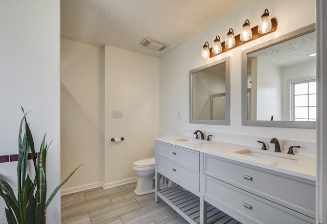 bathroom with vanity, toilet, an enclosed shower, and a textured ceiling