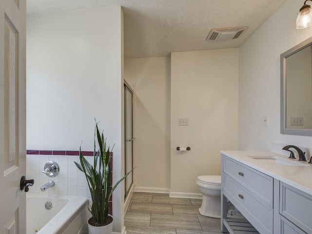 full bathroom with vanity, a textured ceiling, toilet, and separate shower and tub