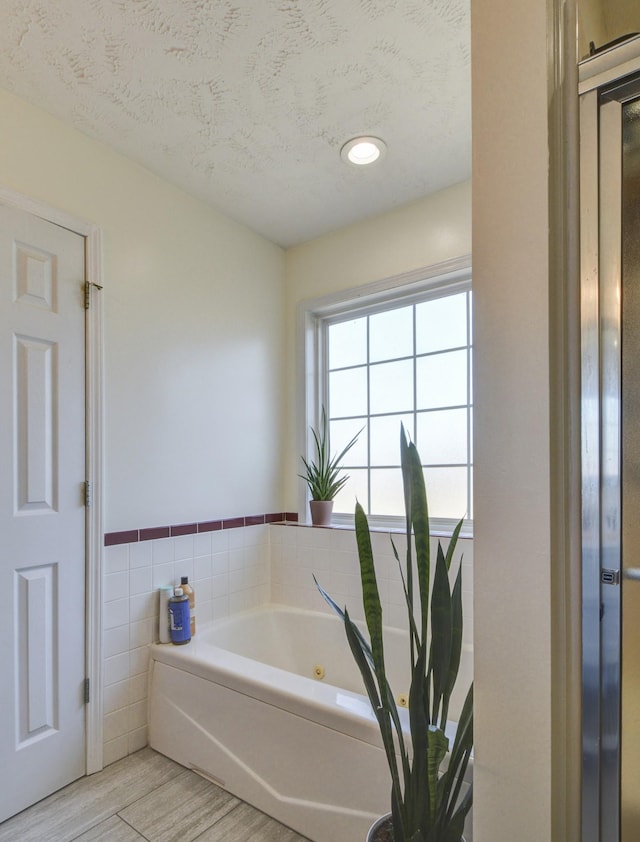 bathroom featuring a bathing tub, wood-type flooring, tile walls, and a textured ceiling