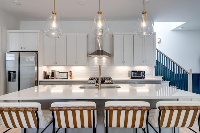 kitchen with wall chimney exhaust hood, a large island, stainless steel fridge with ice dispenser, and decorative backsplash