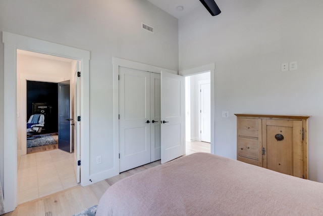 bedroom featuring ceiling fan, high vaulted ceiling, light hardwood / wood-style floors, and a closet