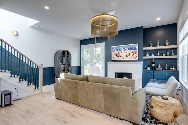 living room with built in shelves, a fireplace, and light hardwood / wood-style flooring