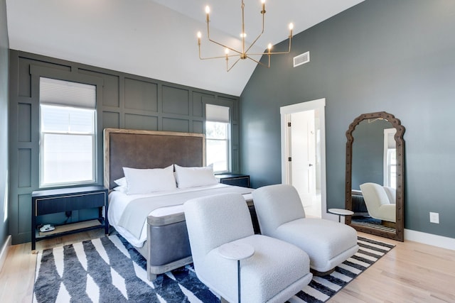 bedroom with an inviting chandelier, high vaulted ceiling, and light hardwood / wood-style floors