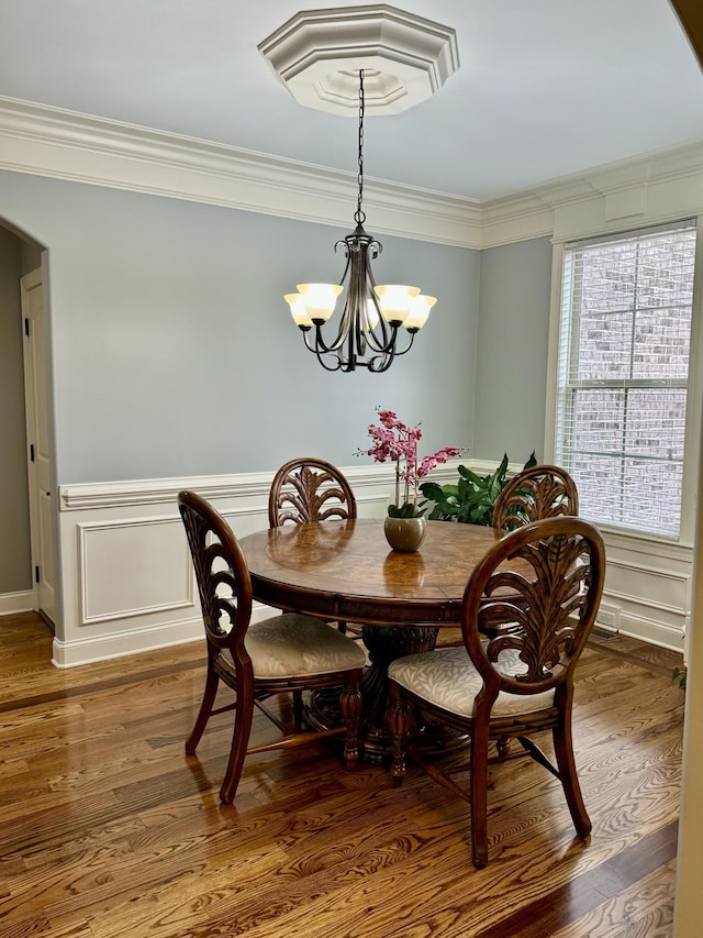 dining area with crown molding, wood-type flooring, and a notable chandelier