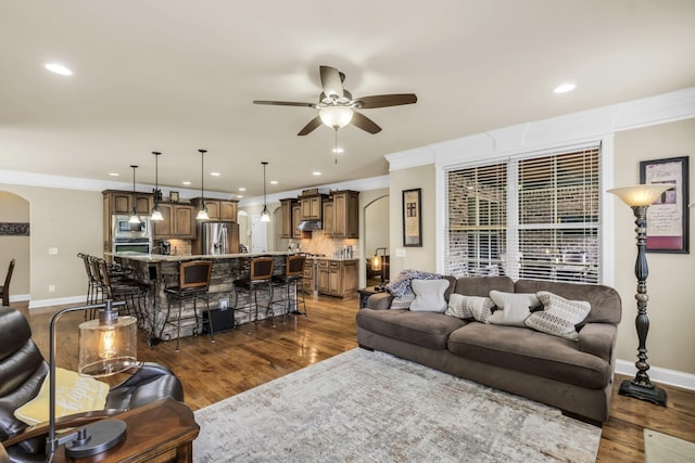 living room with crown molding, dark hardwood / wood-style floors, and ceiling fan