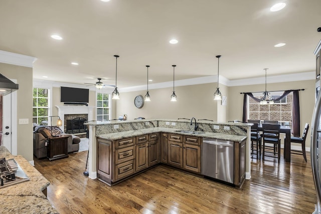 kitchen with sink, light stone counters, decorative light fixtures, dishwasher, and a large island