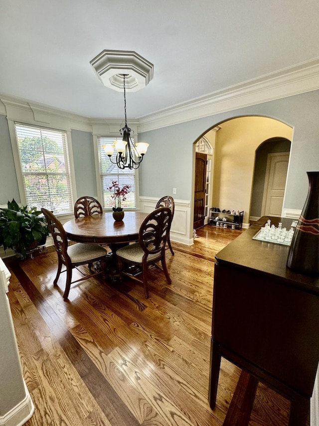 dining area featuring an inviting chandelier, wood-type flooring, and crown molding