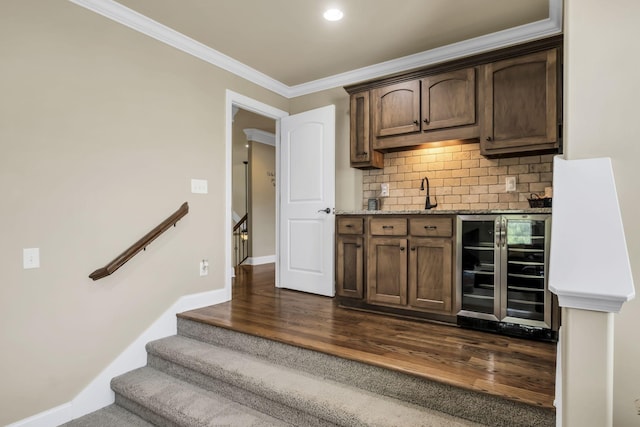 bar with tasteful backsplash, sink, beverage cooler, ornamental molding, and dark wood-type flooring