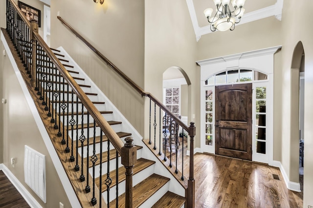 foyer with a high ceiling, crown molding, dark hardwood / wood-style floors, and an inviting chandelier