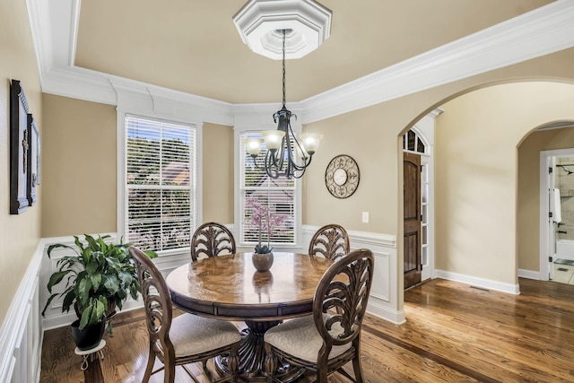 dining space featuring crown molding, hardwood / wood-style floors, and an inviting chandelier