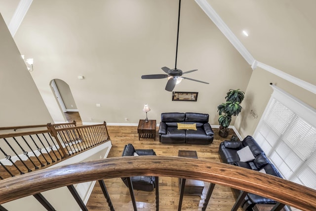 living room with crown molding, ceiling fan, hardwood / wood-style flooring, and a high ceiling