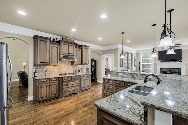 kitchen featuring stainless steel appliances, sink, hanging light fixtures, and a large island with sink