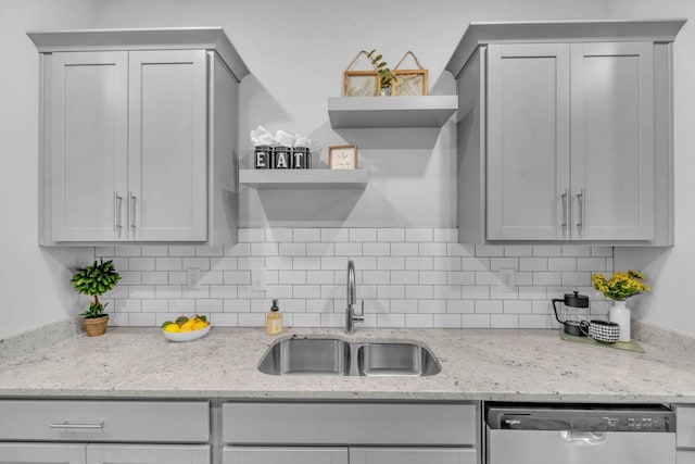 kitchen with dishwasher, sink, light stone countertops, and gray cabinetry