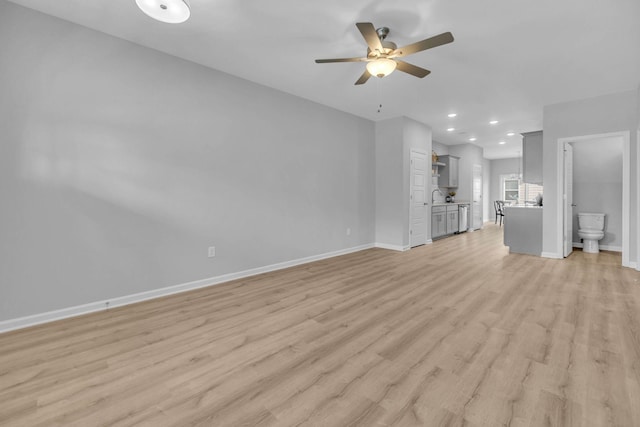 unfurnished living room with ceiling fan, sink, and light wood-type flooring