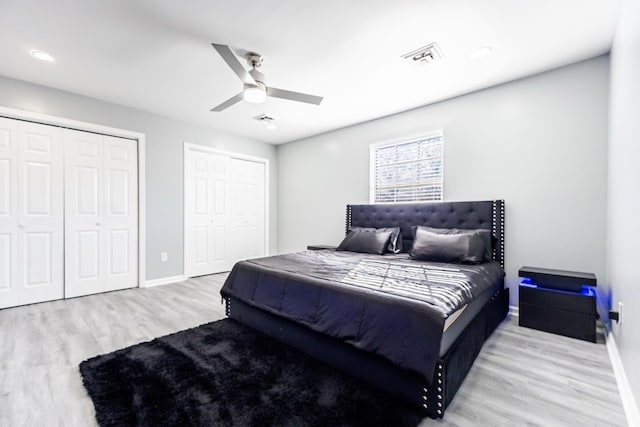 bedroom featuring multiple closets, ceiling fan, and light hardwood / wood-style flooring