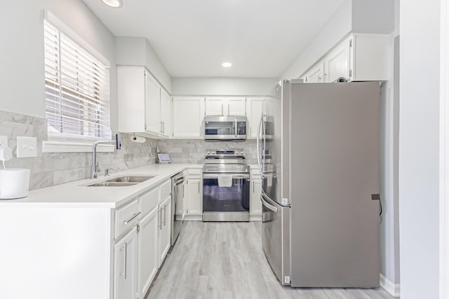 kitchen featuring stainless steel appliances, white cabinetry, sink, and tasteful backsplash