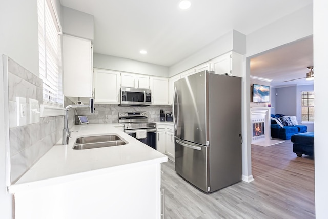 kitchen with stainless steel appliances, white cabinetry, sink, and kitchen peninsula