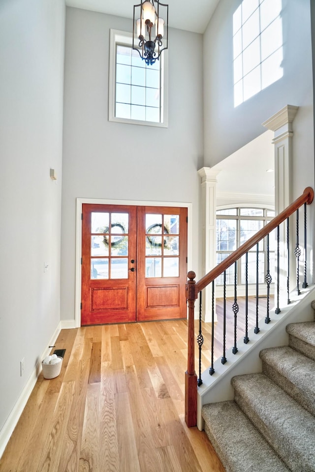 foyer featuring a high ceiling, an inviting chandelier, light hardwood / wood-style floors, and french doors