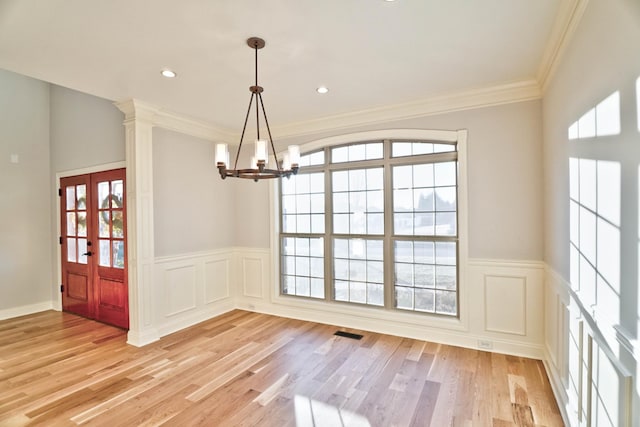 unfurnished dining area featuring crown molding, an inviting chandelier, and light hardwood / wood-style floors