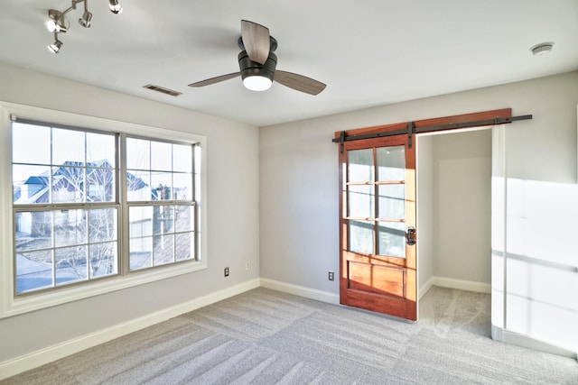 spare room featuring ceiling fan, rail lighting, and light carpet