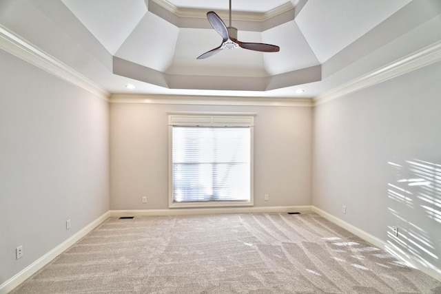 carpeted spare room featuring ornamental molding, a raised ceiling, and ceiling fan