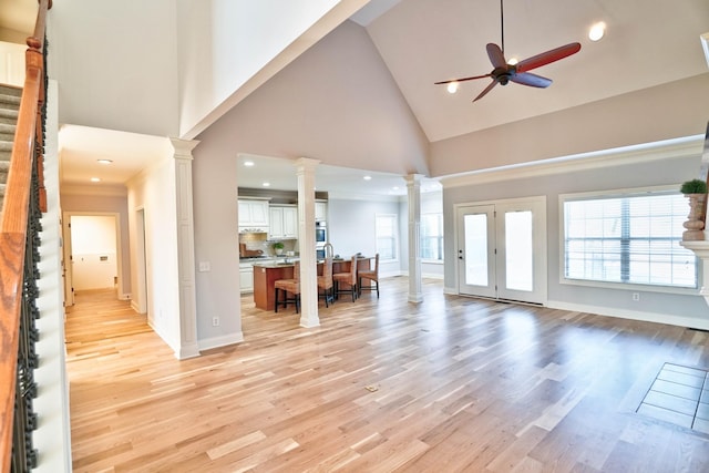 unfurnished living room with a wealth of natural light, decorative columns, and light wood-type flooring