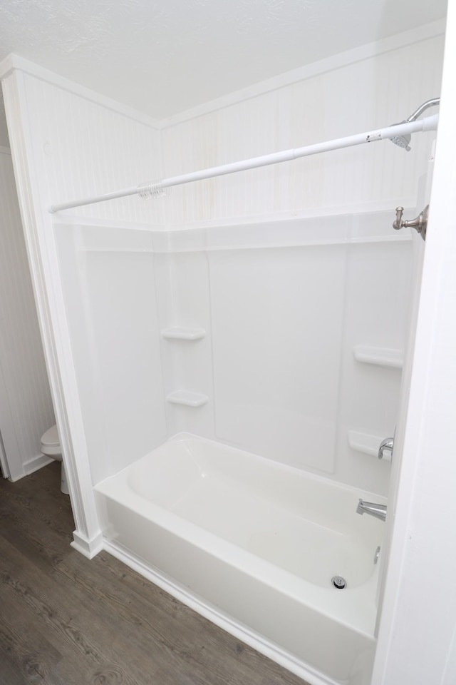 bathroom featuring washtub / shower combination, wood-type flooring, and toilet