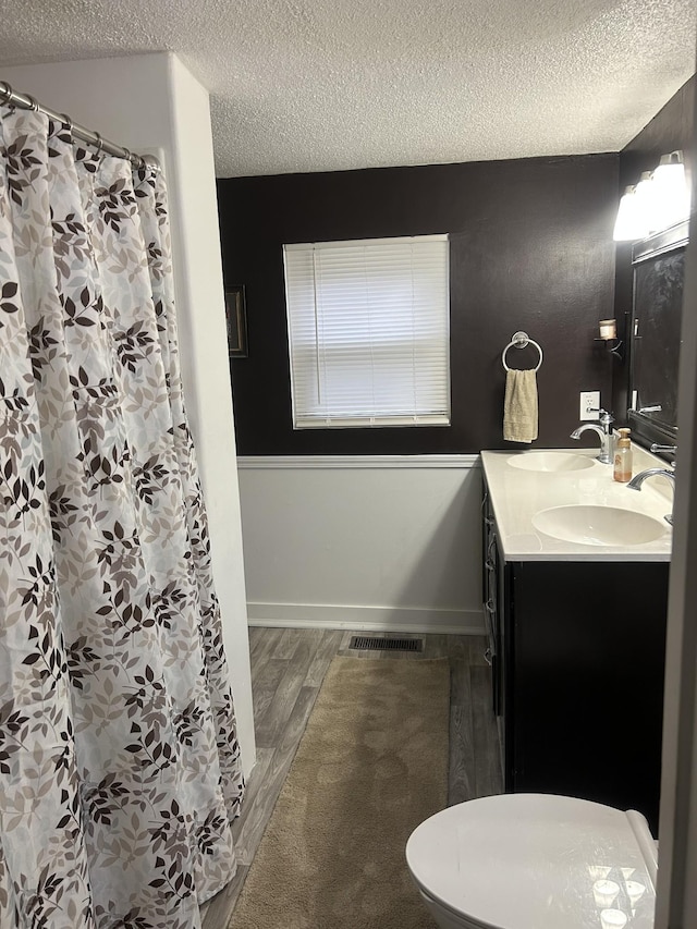 bathroom featuring vanity, hardwood / wood-style flooring, toilet, and a textured ceiling