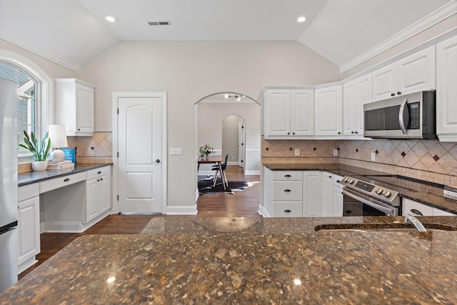 kitchen featuring white cabinetry, lofted ceiling, dark stone counters, and appliances with stainless steel finishes