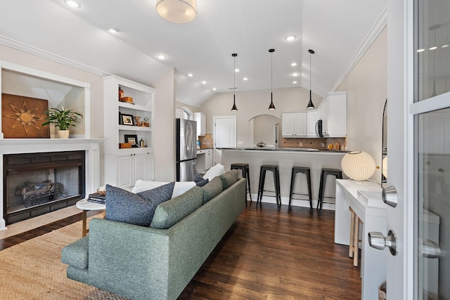 living room with dark wood-type flooring, ornamental molding, and vaulted ceiling