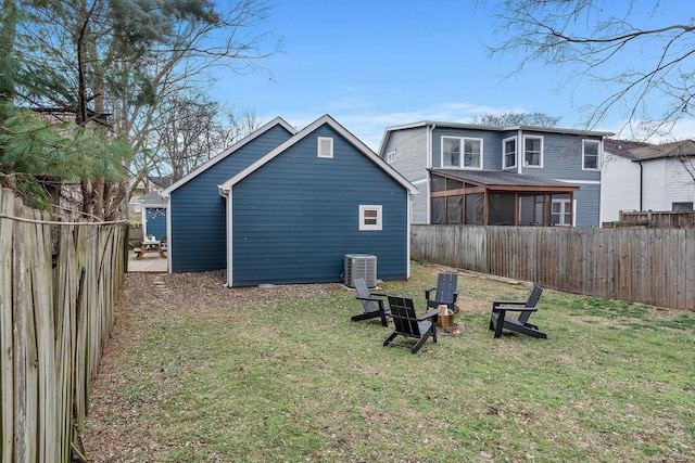 rear view of property featuring a yard, central AC unit, and a sunroom