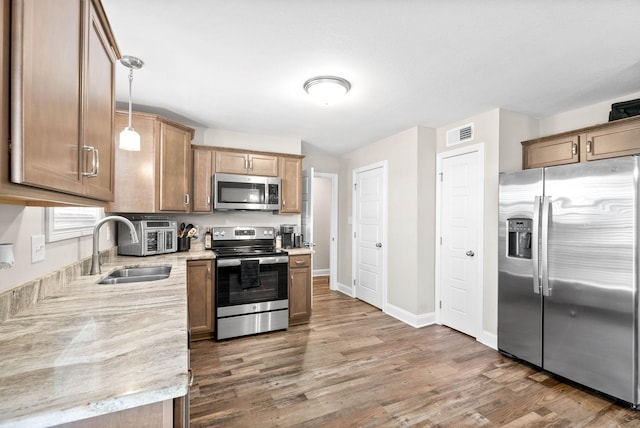 kitchen featuring sink, decorative light fixtures, appliances with stainless steel finishes, dark hardwood / wood-style floors, and light stone countertops