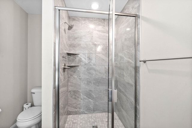 bathroom with a shower with shower door and toilet