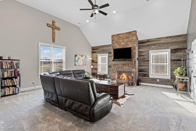 living room with wood walls, high vaulted ceiling, light carpet, ceiling fan, and a fireplace